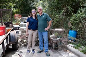 A woman and a man stand together in front of old crab traps.