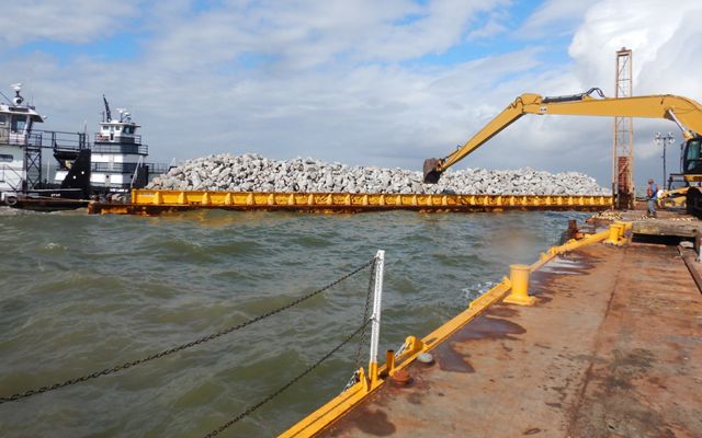 A barge full of limestone boulders to be used for oyster reef construction at Galveston Bay.