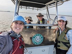 Three women and one man stand on a boat on the ocean.