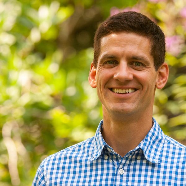 headshot of man smiling in blue checked shirt