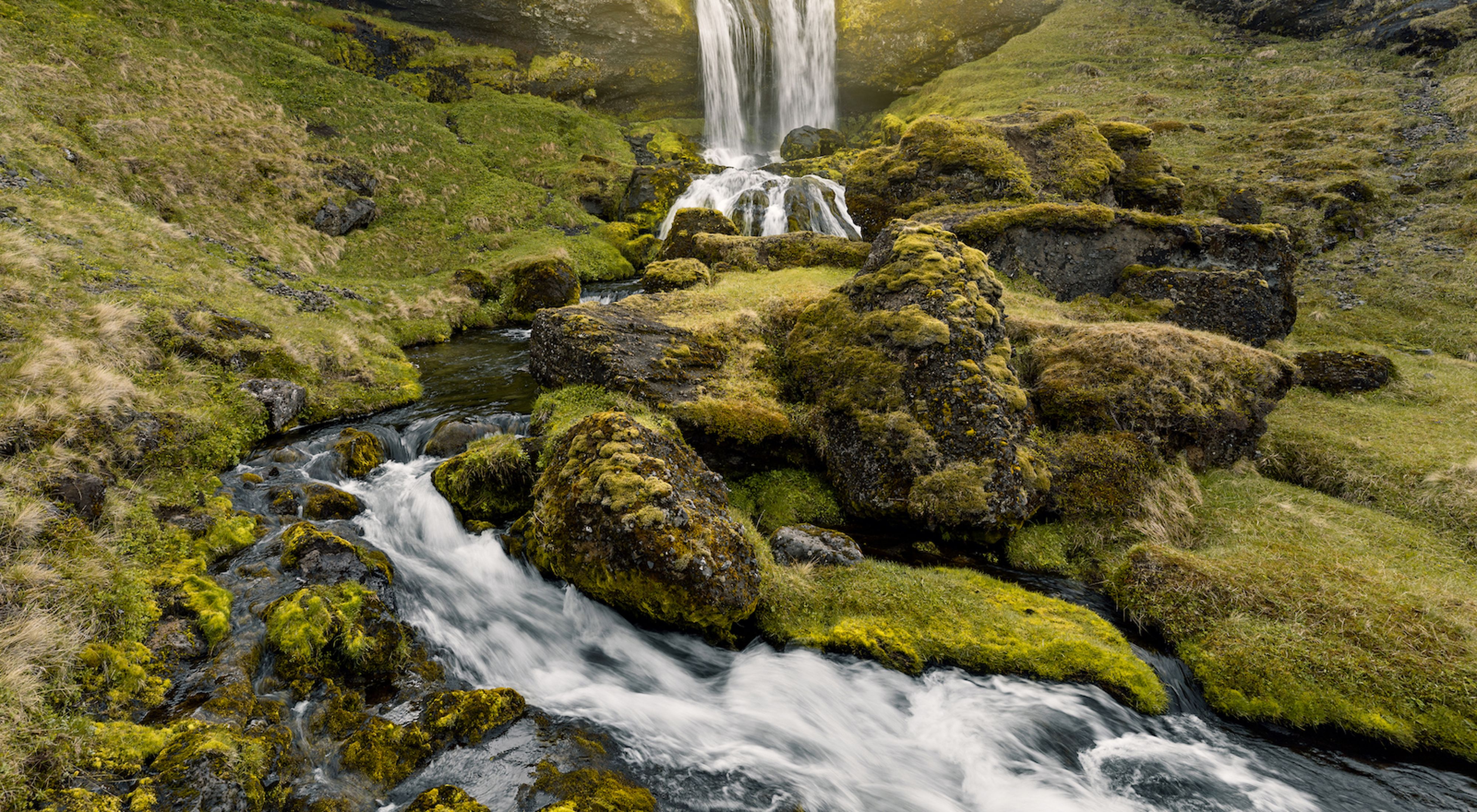 Waterfall cascading around mossy rocks.