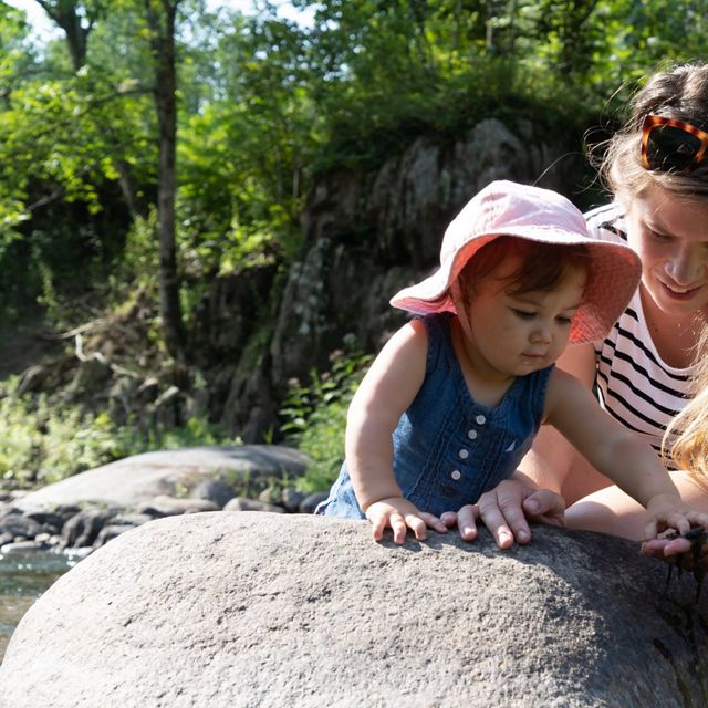 TNC fisheries scientist shows her young daughter how to inspect rocks along a river.