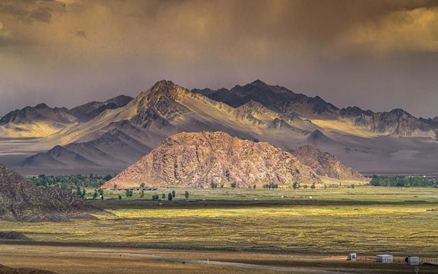 Large mountains with a grassland at the base. 