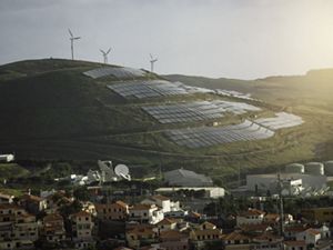 Wind and solar installations dot the hills overlooking a town in Portugal at sunset