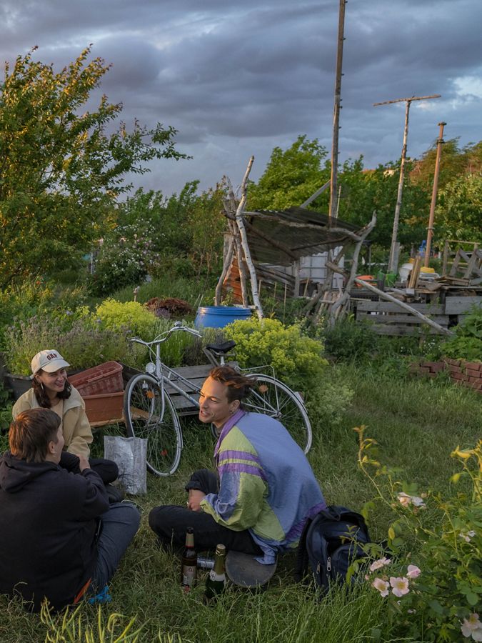 Three Berlin friends sitting in a community garden.