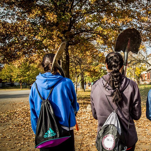 Three young girls walk with garden tools