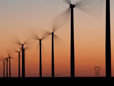 Long-exposure image of windmills rotating in a field at twilight.