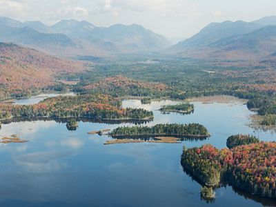 Aerial view of large pond surrounded by forested mountains.