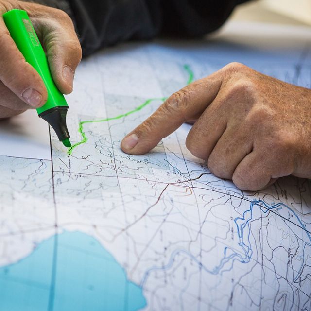 A close up of a hand highlighting a road along a map.