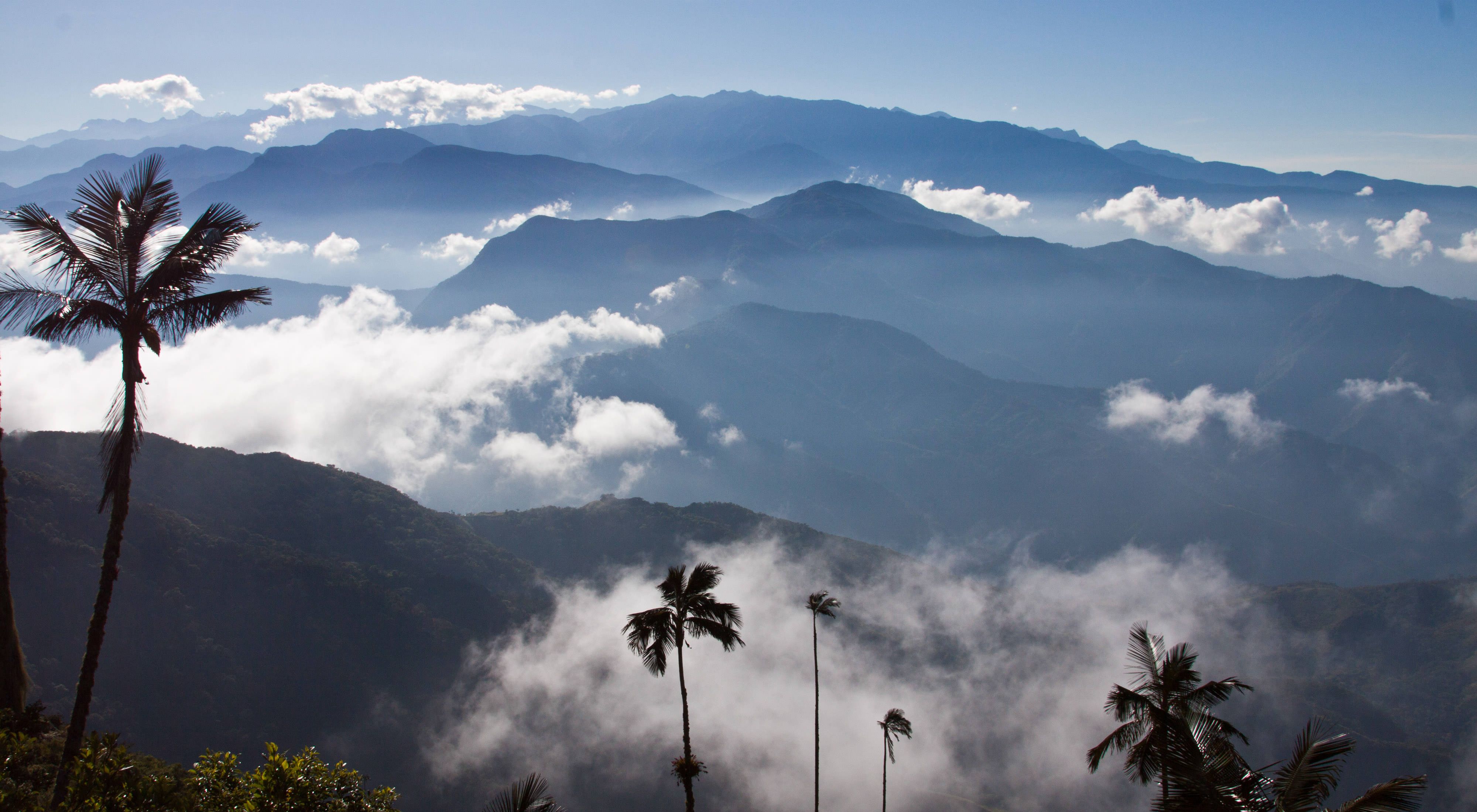 Layers of mountains with white clouds nestled between them.