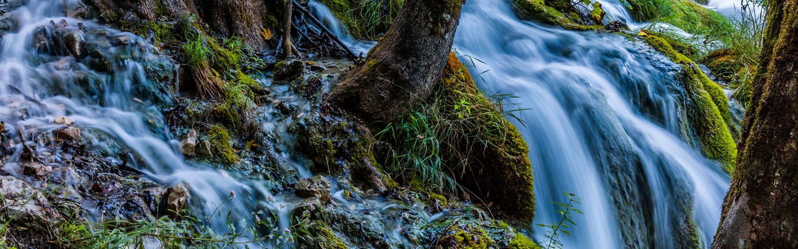 Water falls over moss covered rocks in a preserve in Croatia.